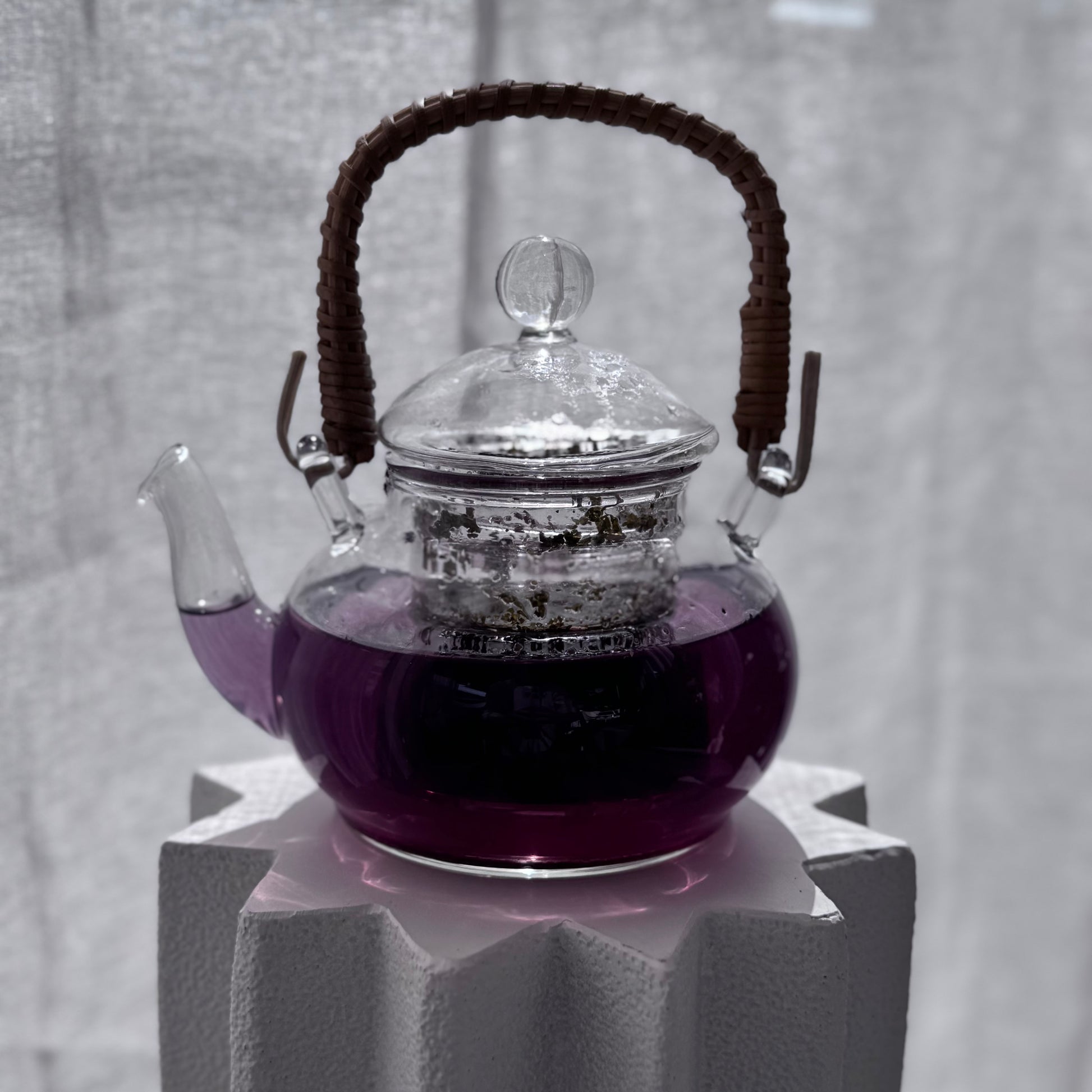 Clear glass teapot with a dark purple tea