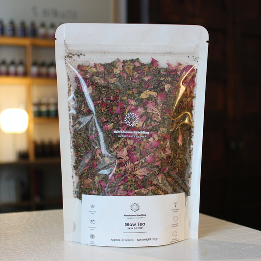 Packaged Glow Tea with visible herbs on a blurred background